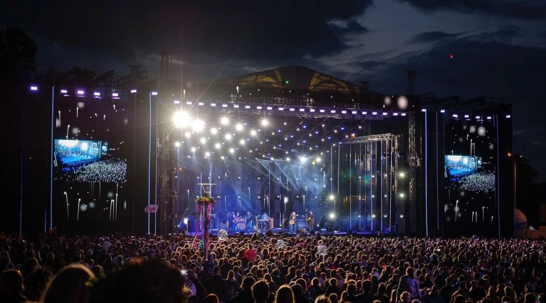 Tłum publiczności ogląda wieczorny koncert na dużej scenie podczas Wianków nad Wisłą w Warszawie.