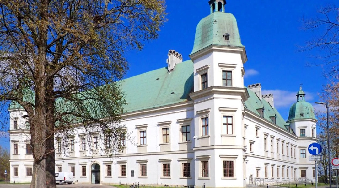 Zamek Ujazdowski w Warszawie widziany od strony ulicy, z białą fasadą i zielonym dachem.