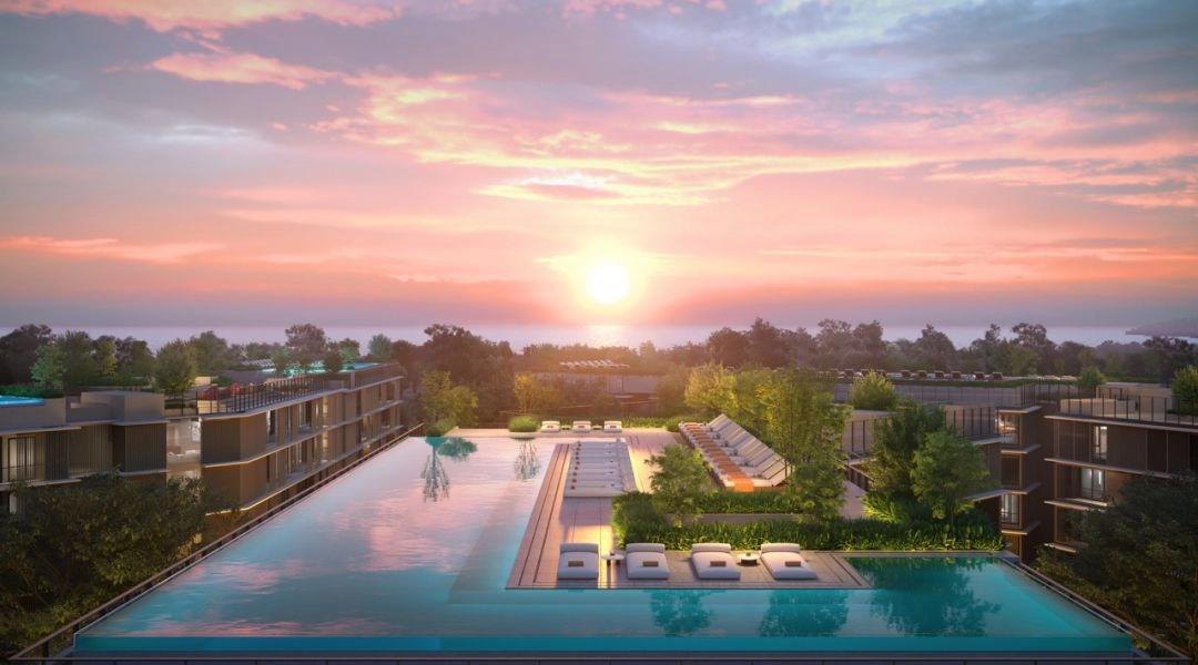 Basen na dachu kompleksu apartamentowego na Phuket o zachodzie słońca, z leżakami i widokiem na morze.