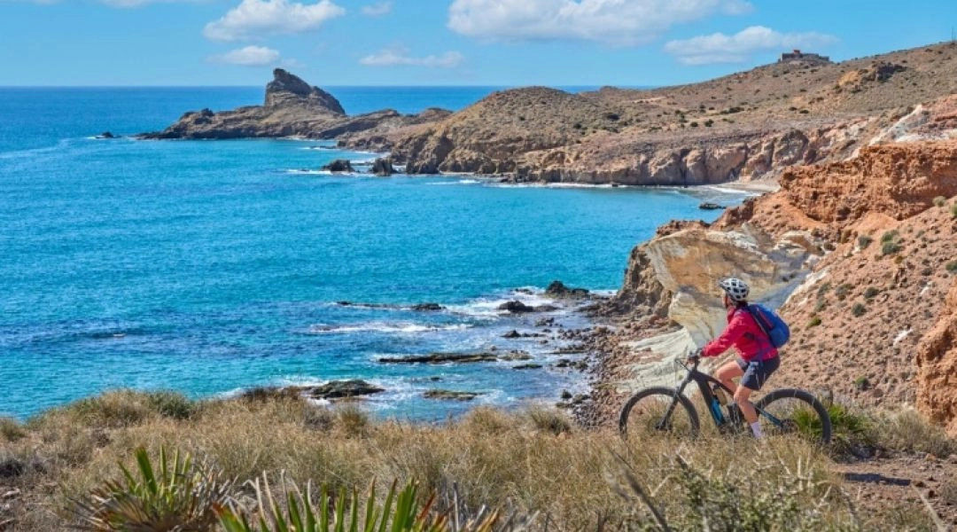 Rowerzystka na trasie wzdłuż skalistego wybrzeża i turkusowego morza w Hiszpanii