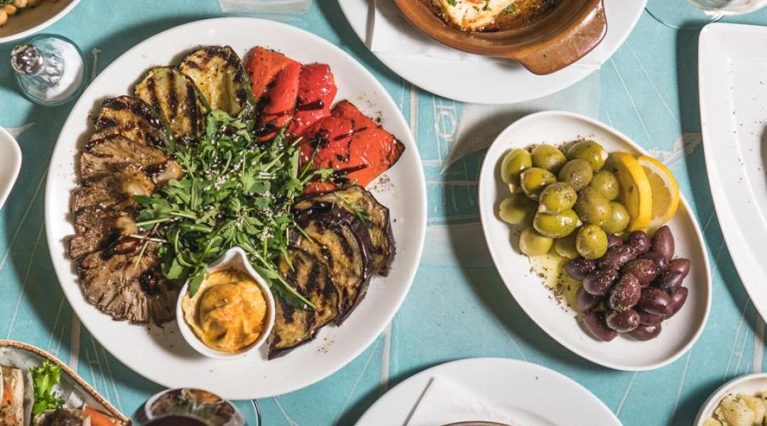 Stół z przystawkami w restauracji Paros, grillowane warzywa, pieczona feta i oliwki