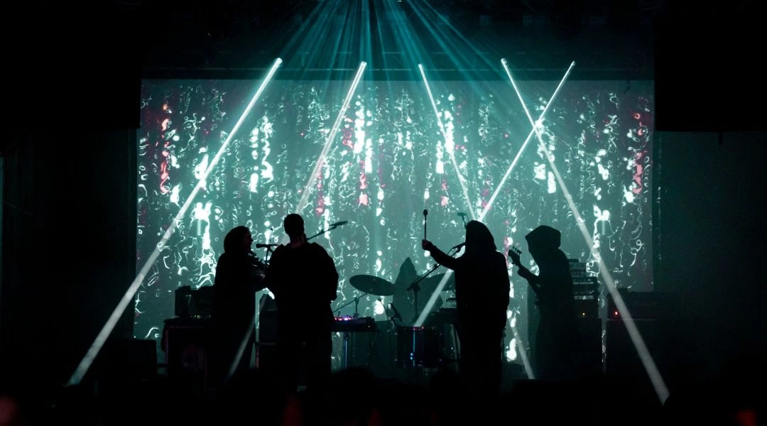 Koncert na Mystic Festival z sylwetkami muzyków na scenie, mocnym światłem i wizualizacjami w tle.