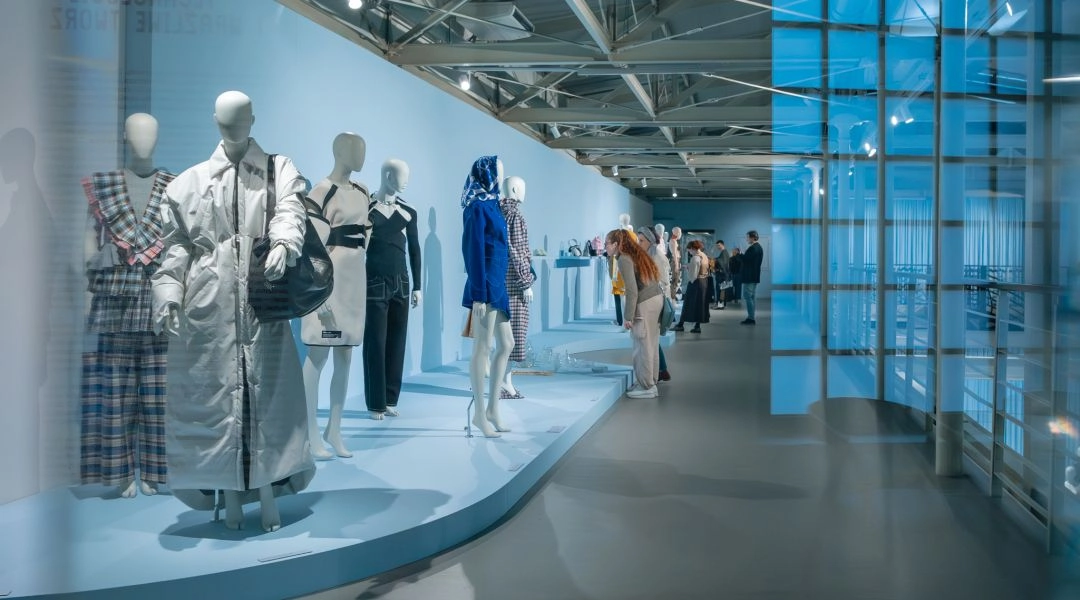 Fragment ekspozycji „Nowa moda polska” z manekinami ustawionymi wzdłuż przeszklonego korytarza muzeum.