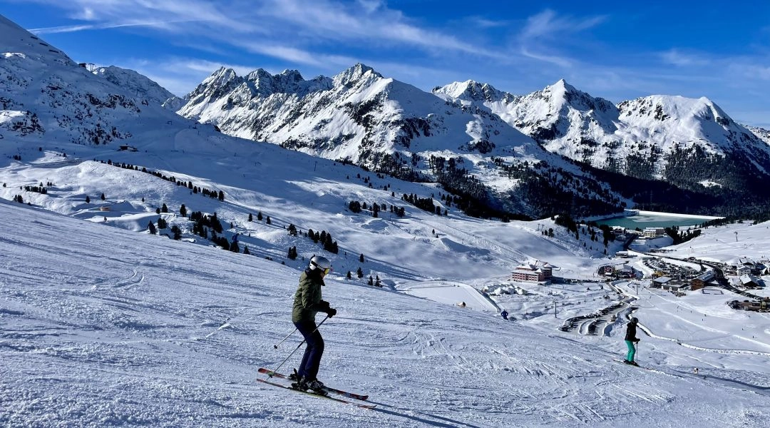 Narciarze na wysokogórskim stoku w Kuhtai, w tle rozległe, ośnieżone szczyty