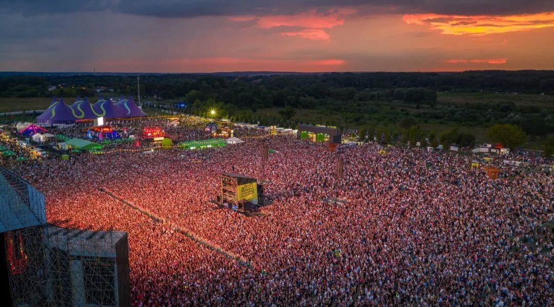 Widok z góry na ogromny tłum uczestników Łódź Summer Festival na Łódzkich Błoniach o zachodzie słońca.