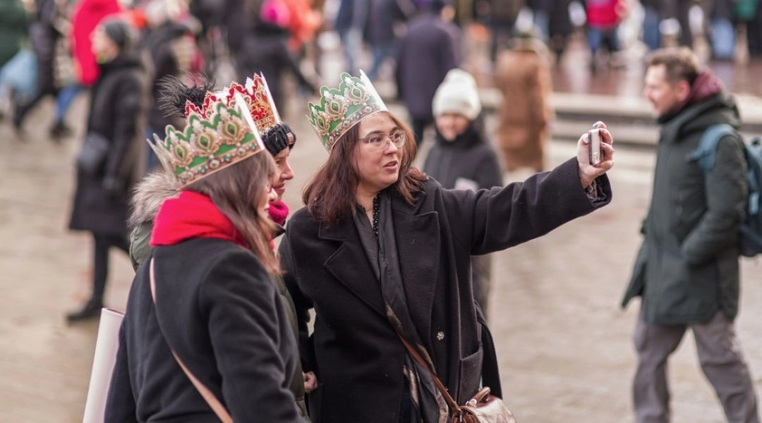 Uczestniczki Orszaku Trzech Króli w papierowych koronach robiące selfie na Placu Zamkowym w Warszawie