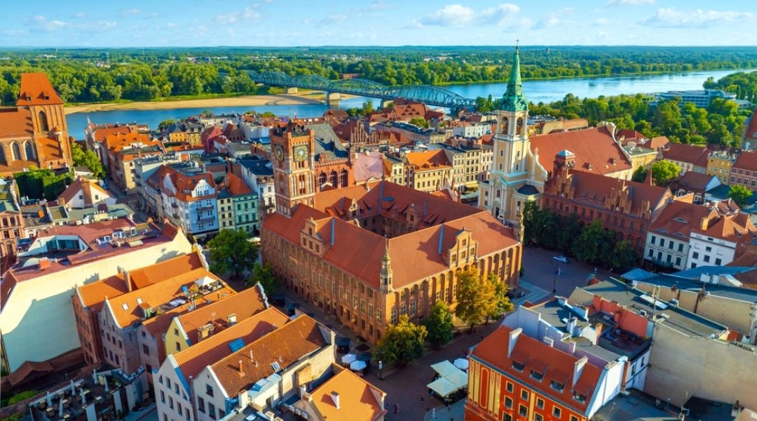 Widok z góry na Stare Miasto w Toruniu, czerwone dachy, ratusz i Wisłę w tle.