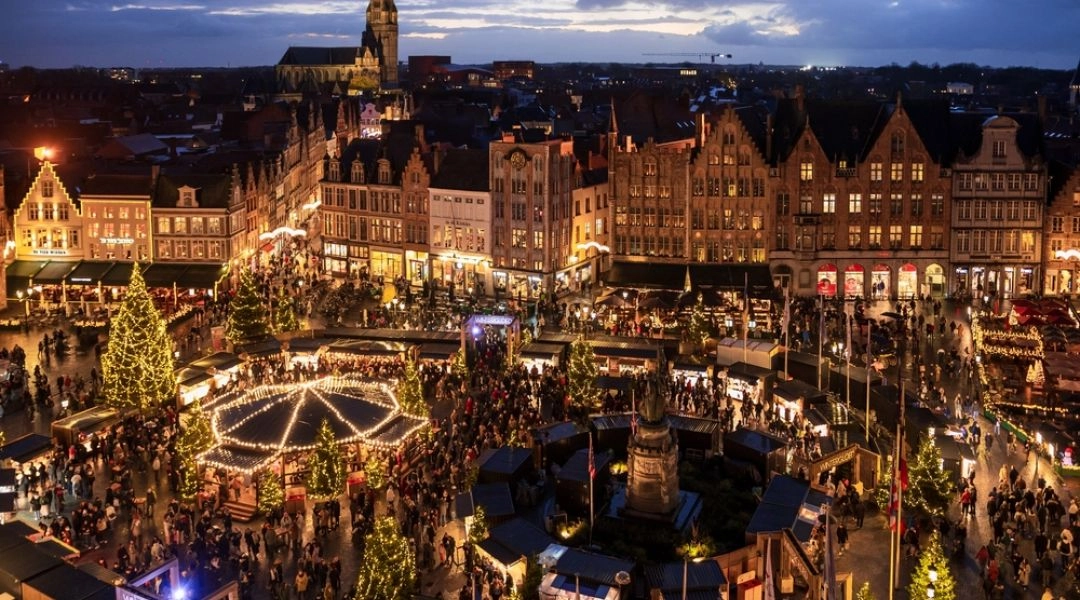 Brugia w okresie świątecznym, jarmark bożonarodzeniowy na rynku i oświetlone kamienice starego miasta.