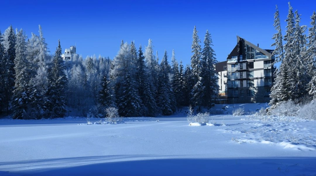 Hotel nad zamarzniętym jeziorem Štrbské Pleso w zimowym krajobrazie