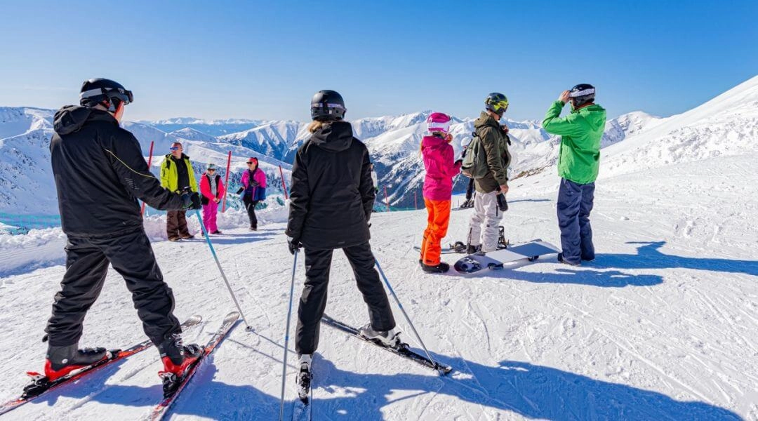 Narciarze i snowboardziści na trasie na Kasprowym Wierchu, w słoneczny dzień, na tle wysokogórskiego krajobrazu Tatr