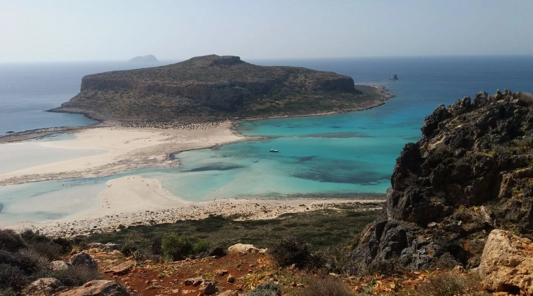 Panorama laguny Balos na Krecie z turkusową wodą, jasnymi plażami i skalistym wybrzeżem.