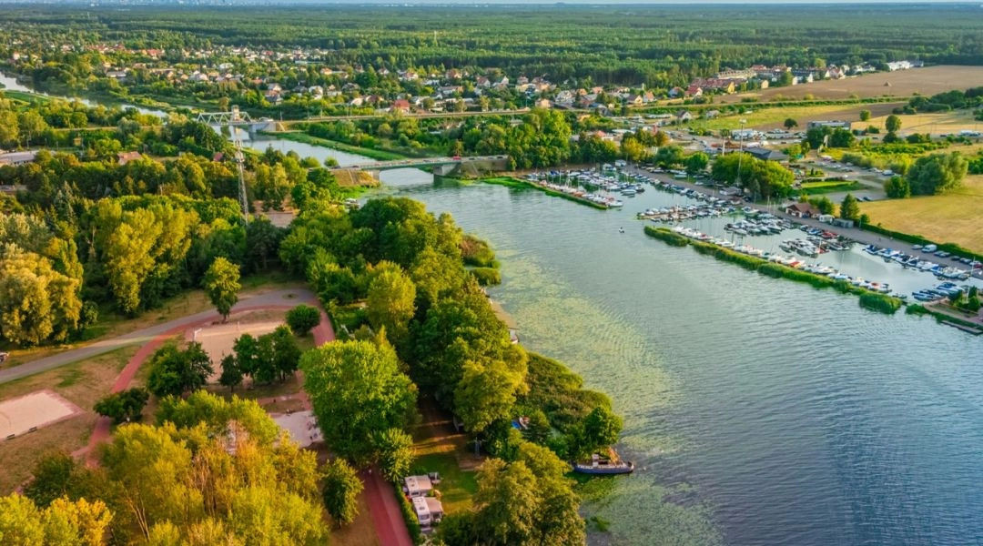 Widok z lotu ptaka na Kanał Żerański i okolice Nieporętu z mariną, zielenią i zabudową w tle.