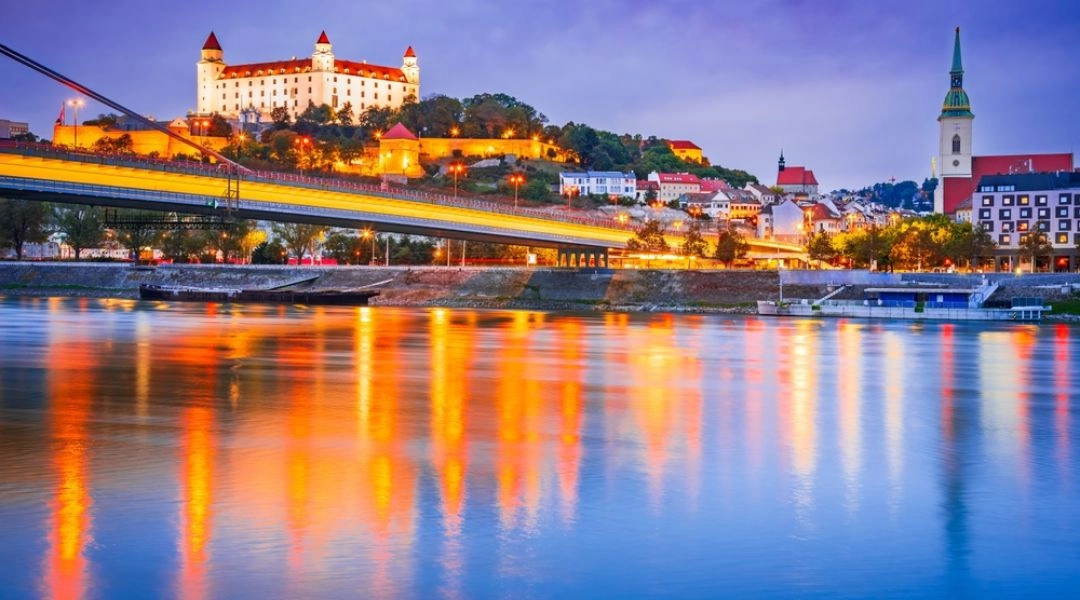 Bratysława nocą z zamkiem na wzgórzu i mostem SNP nad Dunajem