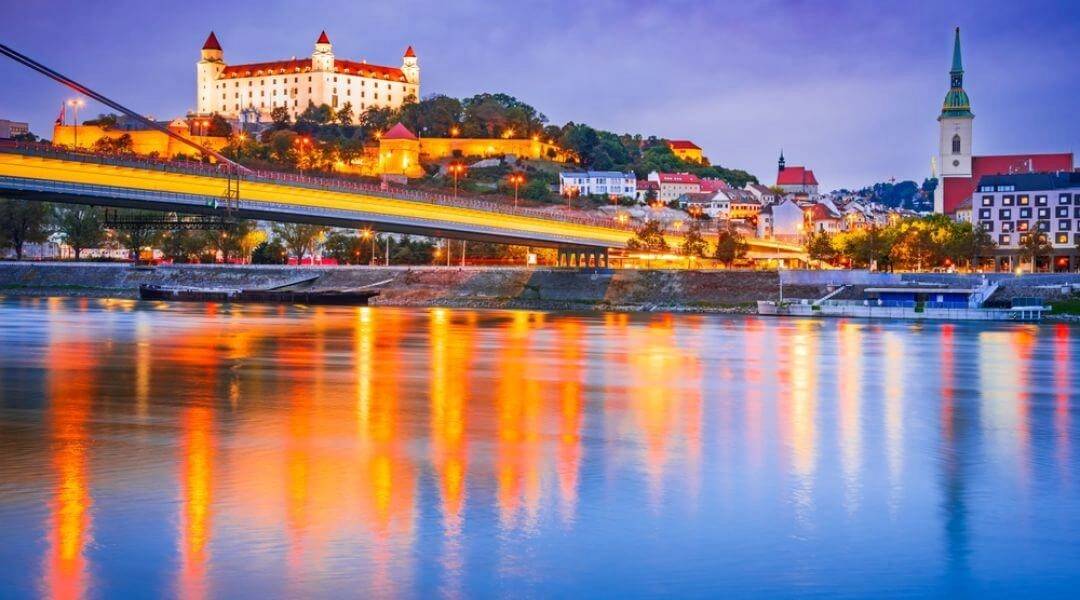 Bratysława nocą z zamkiem na wzgórzu i mostem SNP nad Dunajem