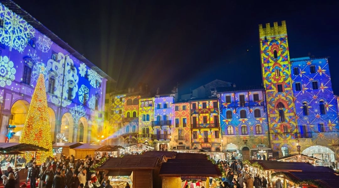 Świąteczne iluminacje i jarmark bożonarodzeniowy w Arezzo we Włoszech, kolorowo podświetlone kamienice i choinka na placu Piazza Grande.