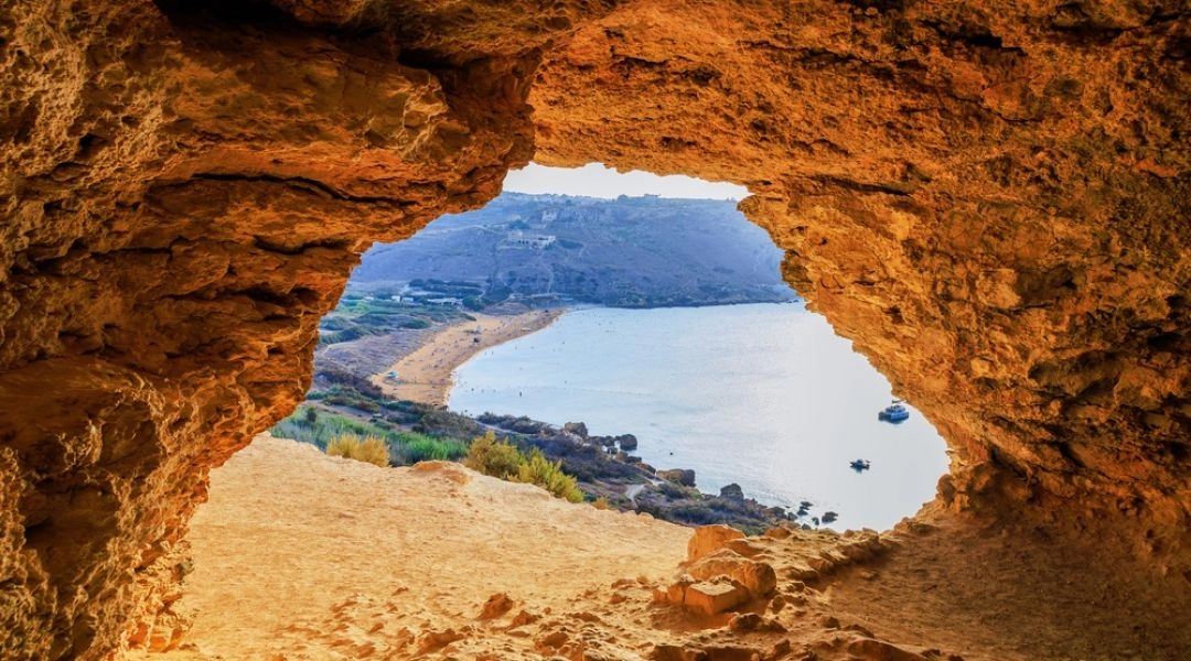Widok z jaskini Mixta na piaszczystą plażę Ramla Bay i zatokę na wyspie Gozo na Malcie.