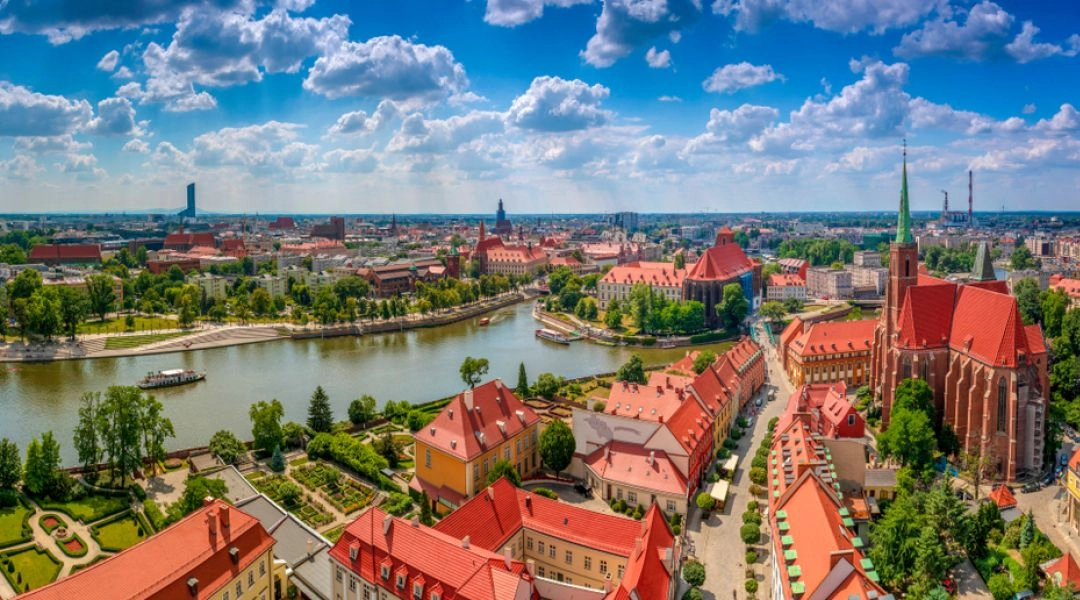 Panorama Wrocławia z Odrą, katedrą i czerwonymi dachami starówki widziana z góry w słoneczny dzień.
