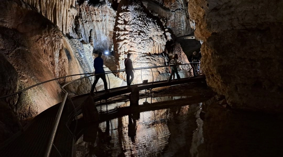 Autor zwiedzający wnętrze sardyńskiej jaskini wśród stalaktytów, stalagmitów i podziemnych zbiorników wodnych.