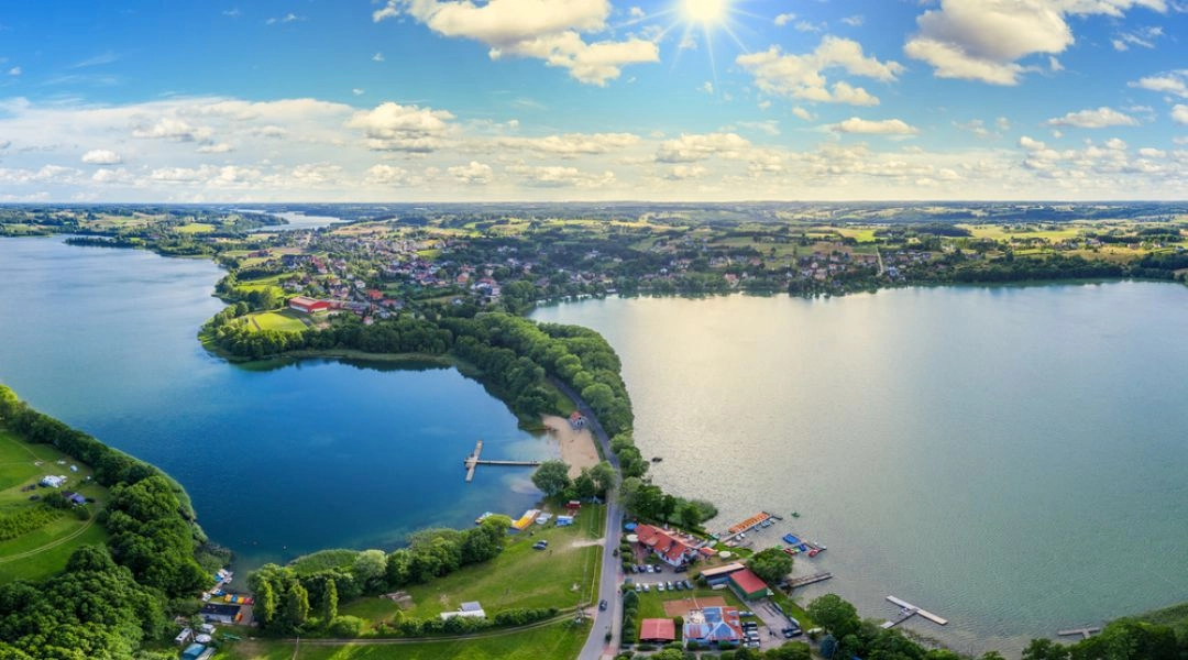 Panorama Chmielna położonego między kaszubskimi jeziorami, z plażą i pomostami nad wodą.
