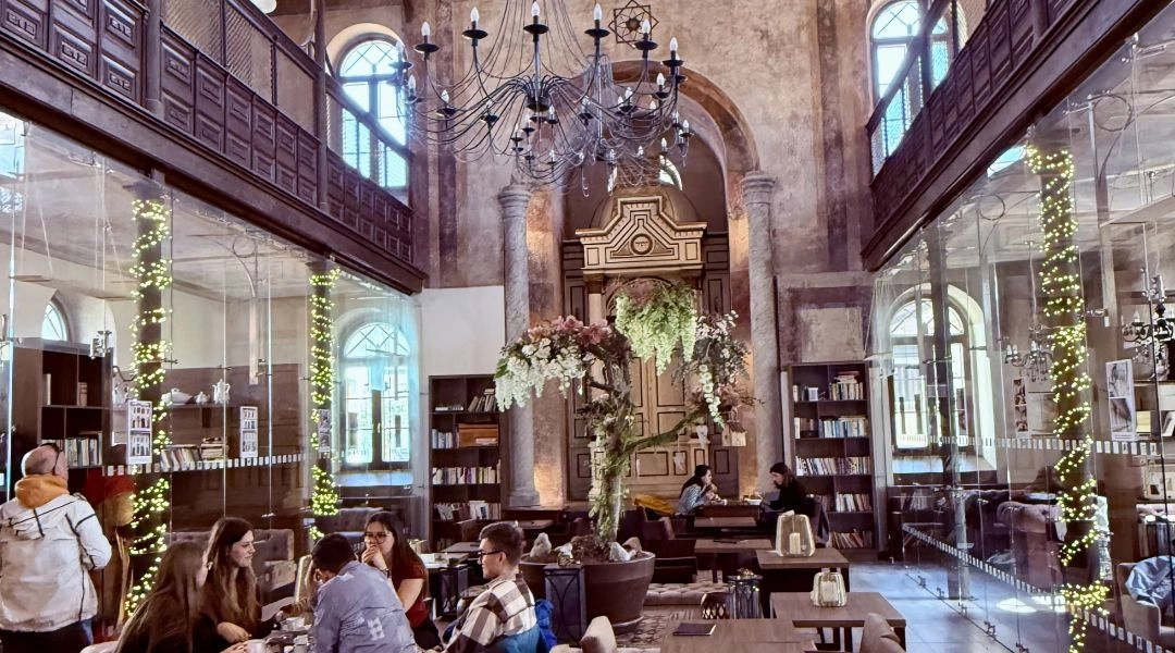 Wnętrze Synagóga Café w Trnawie z zachowanymi balkonami, wysokimi oknami, gwiazdą Dawida i stolikami kawiarni.