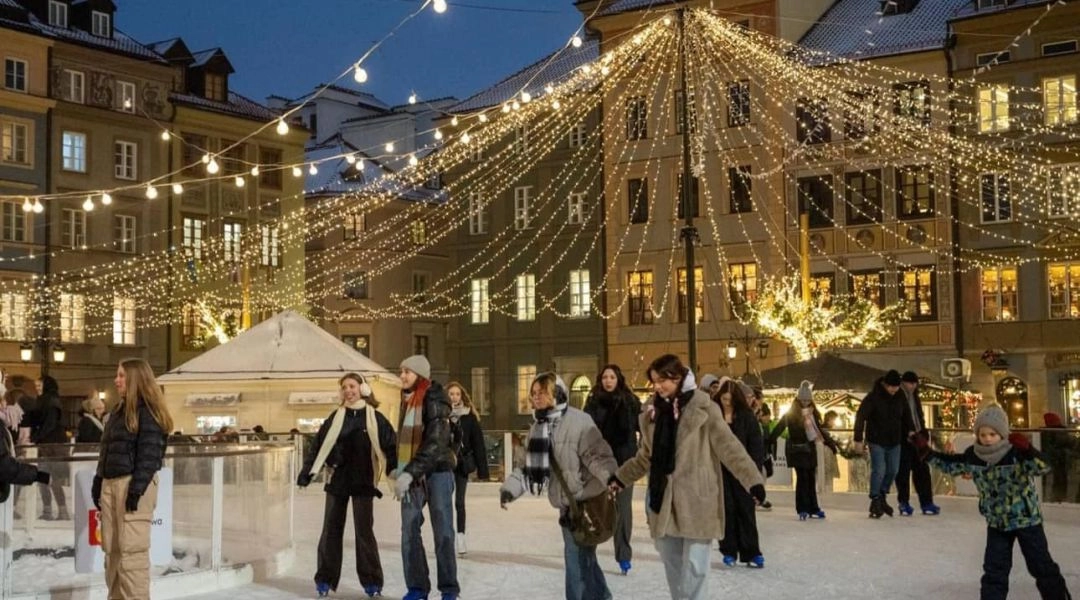 Lodowisko na Rynku Starego Miasta w Warszawie z osobami jeżdżącymi na łyżwach wieczorem.