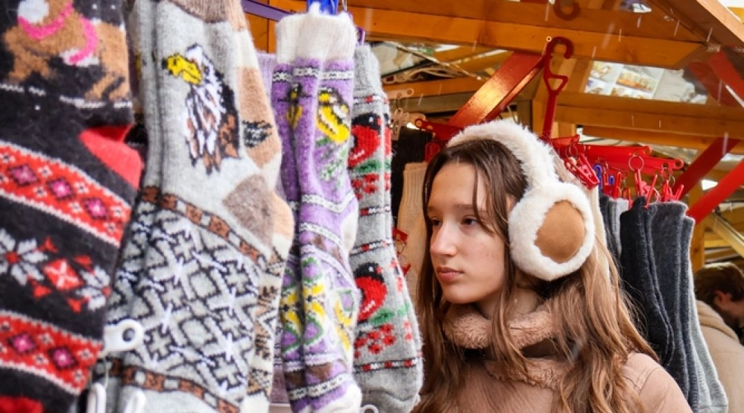 Kobieta ogląda wełniane skarpety i rękodzieło z wełny na jarmarku świątecznym w Warszawie.