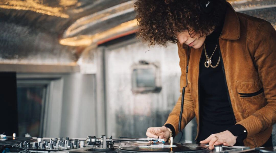 Osoba miksująca muzykę przy gramofonie i konsolecie DJ podczas warsztatów.