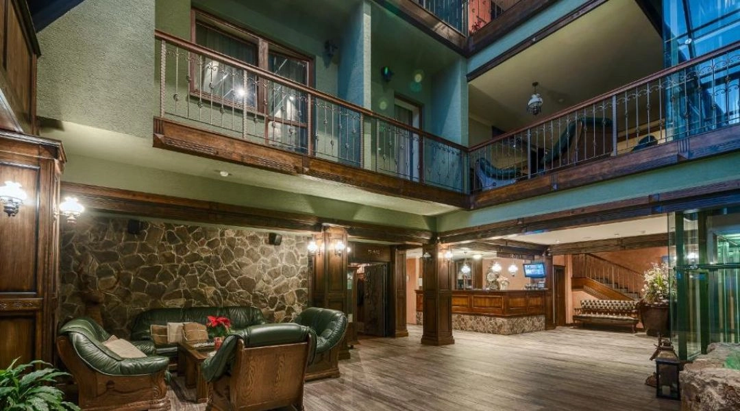 Lobby i recepcja Hotelu Borovica z kamiennymi ścianami, drewnianymi balkonami oraz skórzanymi fotelami.