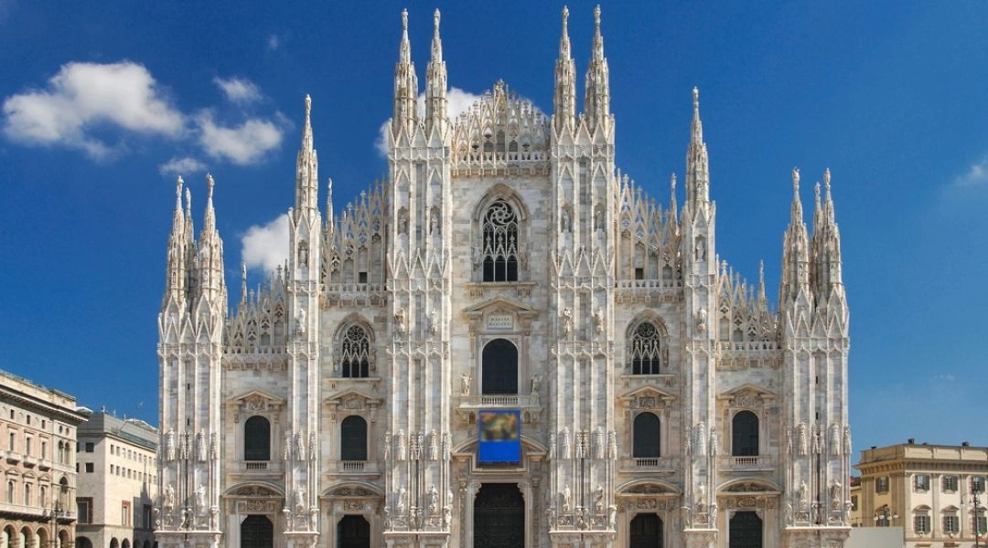 Katedra Duomo w Mediolanie widziana z Piazza del Duomo, w słoneczny zimowy dzień z turystami przed wejściem.