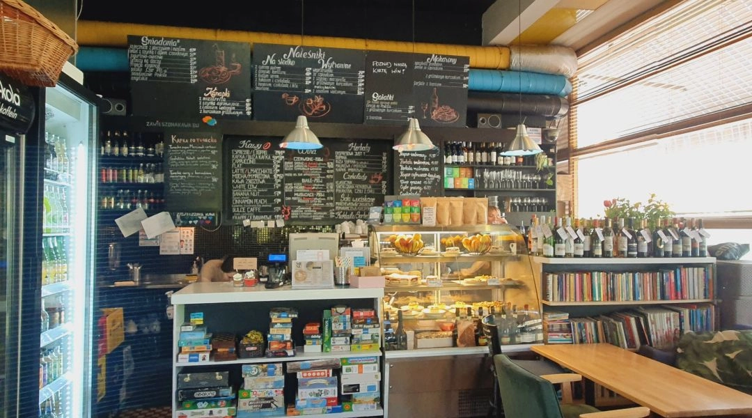Wnętrze kawiarni Kafka w Warszawie z ladą i tablicami menu.