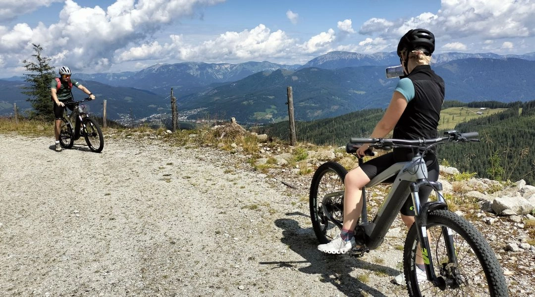 Rowerzyści na rowerach elektrycznych na górskiej trasie w Hochsteiermarku z widokiem na Alpy