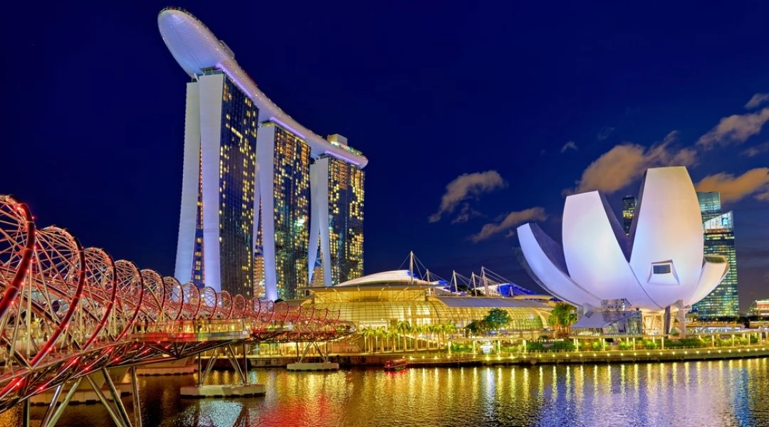 Marina Bay w Singapurze nocą z hotelem Marina Bay Sands, mostem Helix Bridge i budynkiem ArtScience Museum nad zatoką