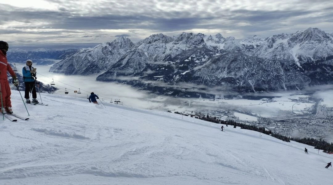 Narciarze na trasie Zettersfeld z widokiem na dolinę Lienz i Dolomity Lienzkie.