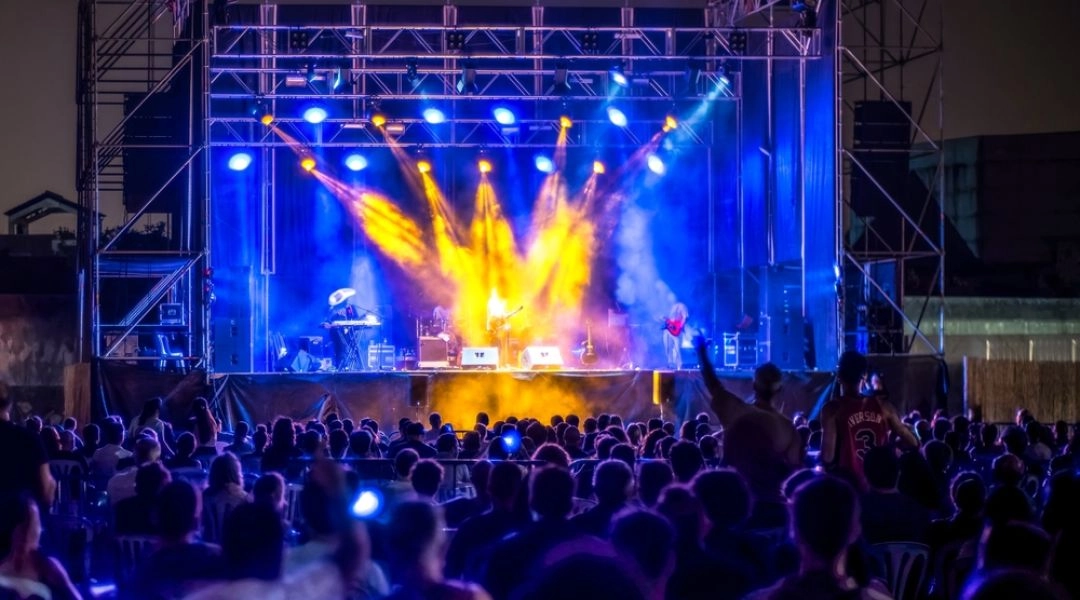 Nocny koncert na plenerowej scenie Open’er Festival z niebieskim i pomarańczowym oświetleniem oraz publicznością przed sceną.