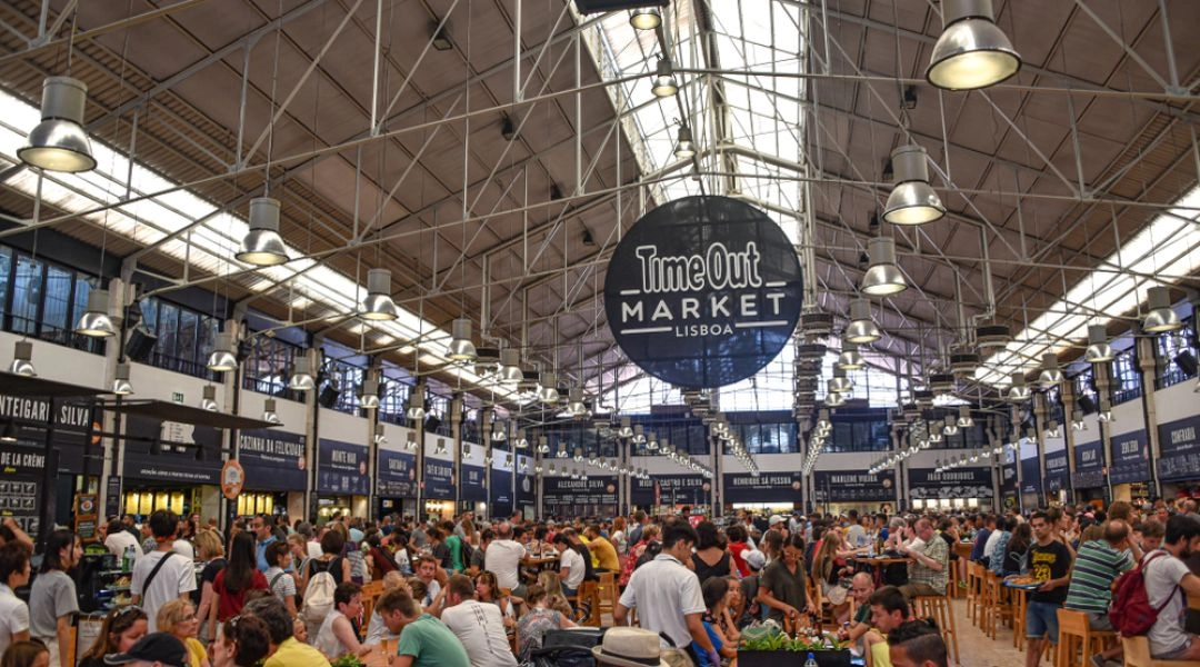 Time Out Market Lizbona wnętrze hali targowej z restauracjami i wspólnymi stołami.