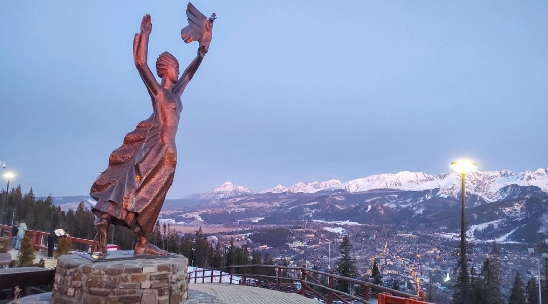 Panorama Zakopanego z Gubałówki i pomnik na tle Tatr o zachodzie słońca
