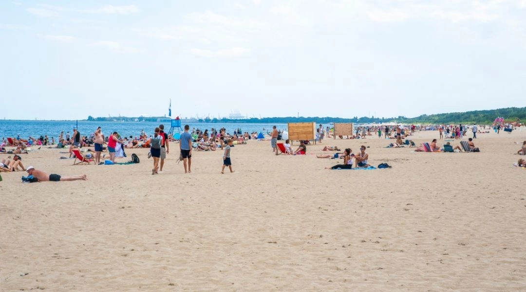 Piaszczysta plaża w gdańskim Jelitkowie z turystami odpoczywającymi nad morzem w letni dzień.