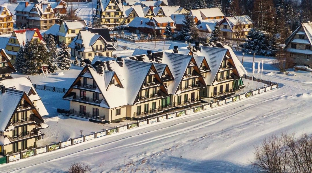 Nowoczesne apartamenty w zimowym kurorcie, ośnieżone dachy i spokojna okolica w ciągu dnia.