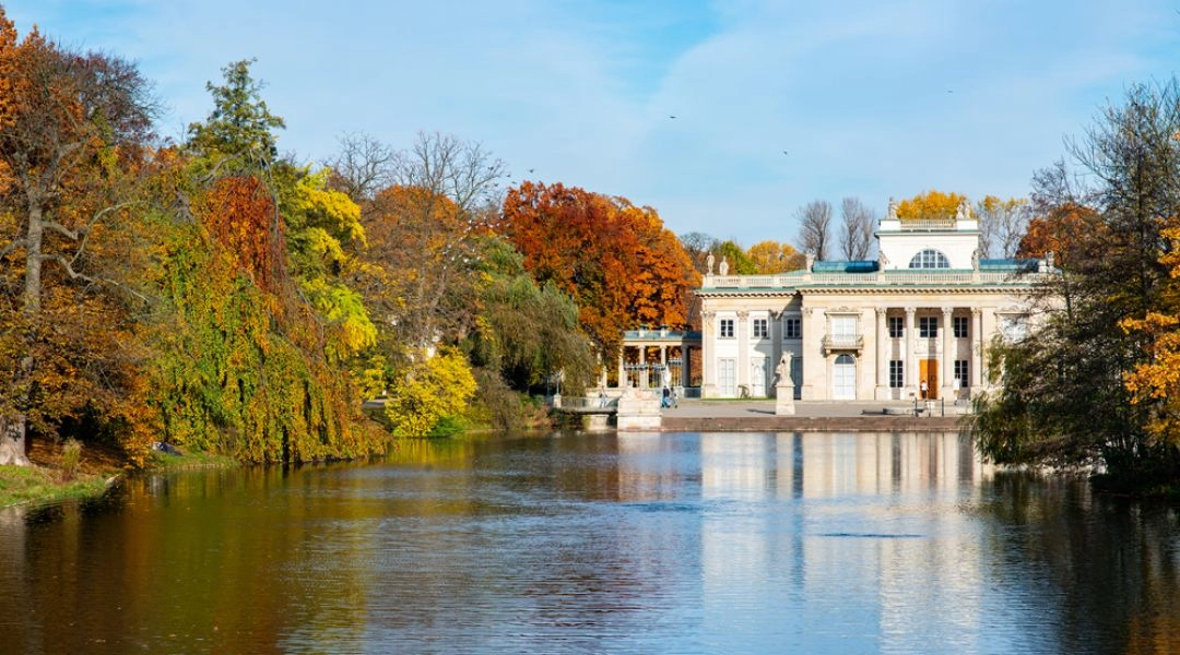 Pałac na Wyspie w Łazienkach Królewskich otoczony jesiennymi drzewami i odbijający się w stawie