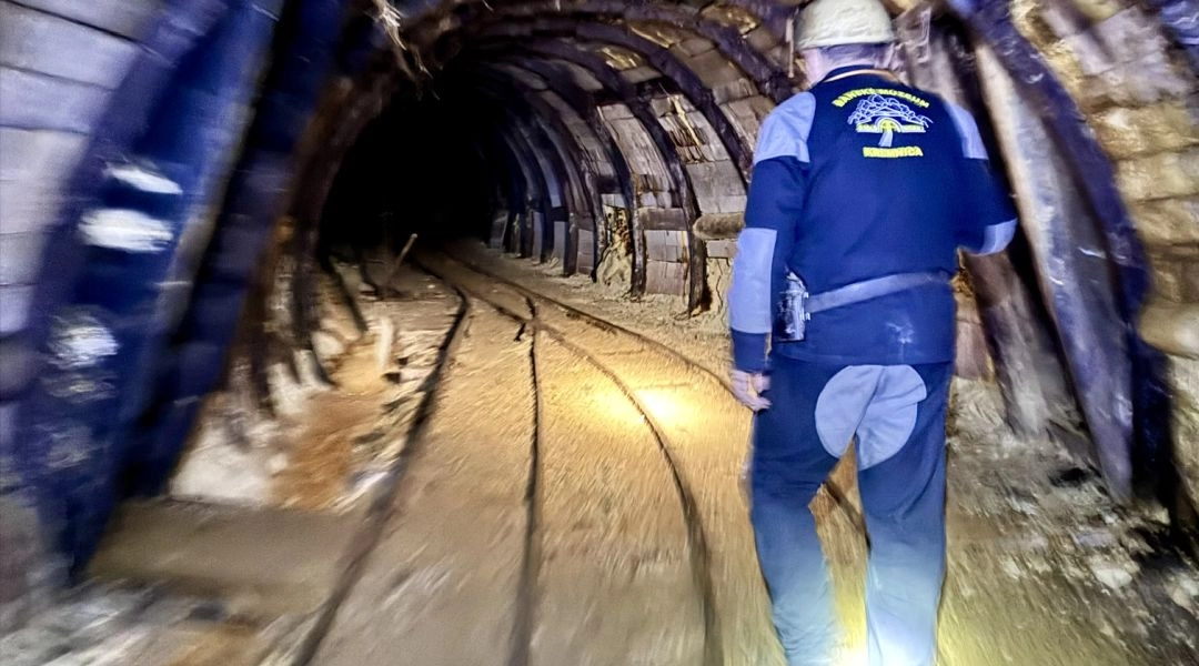 Wnętrze dawnej kopalni złota w Kremnicy, z drewnianymi podporami i wąskimi torami prowadzącymi przez podziemny korytarz.