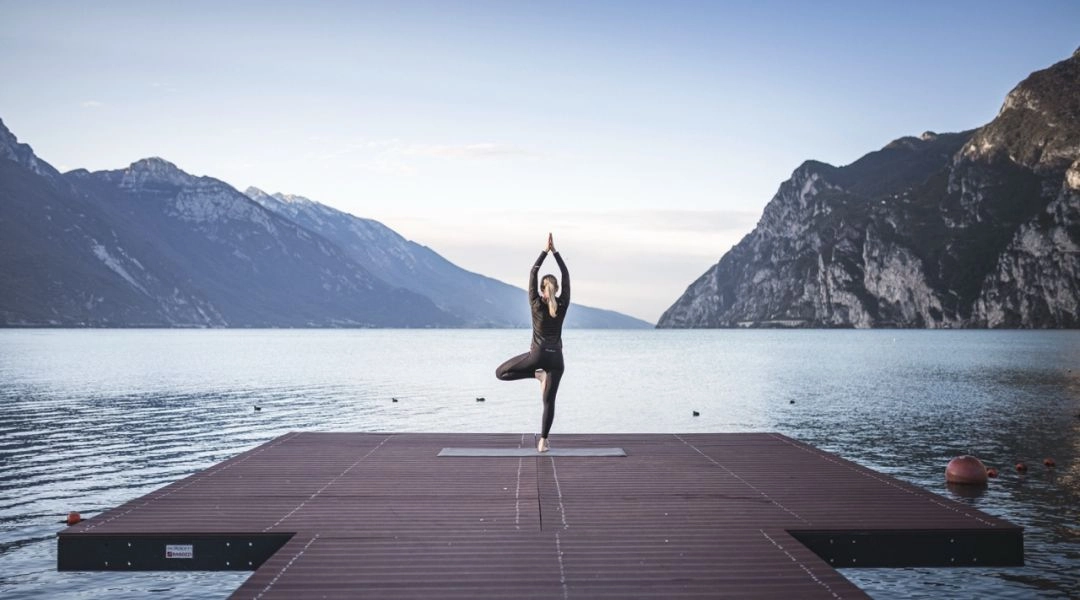 Joga nad jeziorem Garda w Trentino, ćwiczenia na pomoście z widokiem na alpejskie góry.