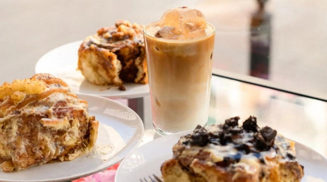Cynamonki z kremowymi polewami i dodatkami oraz mrożona kawa w Canela Bakery w Warszawie.