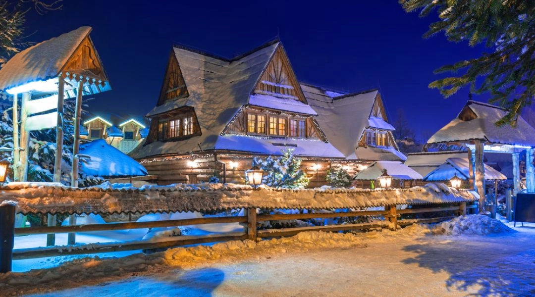 Zimowy wieczór w górskim kurorcie w Polsce, ośnieżone domy i nastrojowe oświetlenie.