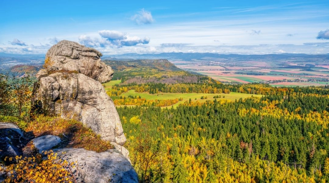 Piaskowcowa formacja na Szczelińcu Wielkim z panoramą lasów w jesiennych kolorach, pól i odległych wzgórz.