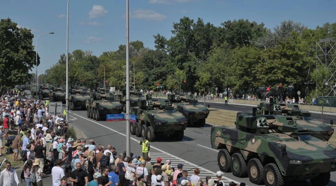Kolumna opancerzonych pojazdów wojskowych przejeżdżająca Wisłostradą w Warszawie w obecności zgromadzonych widzów.