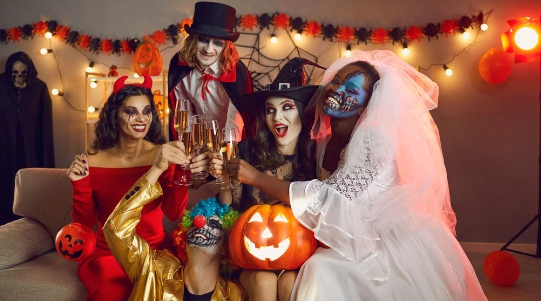 Grupa osób w halloweenowych przebraniach wznosi toast podczas imprezy w Warszawie.