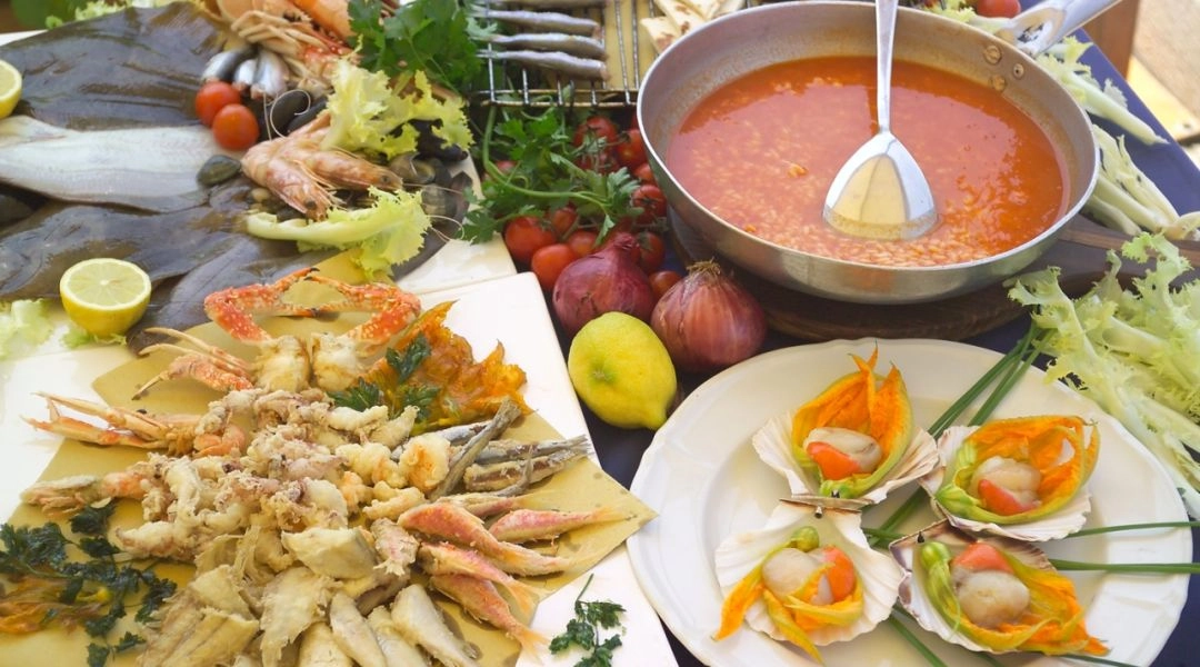 Stół zastawiony świeżymi owocami morza, smażonymi rybami i zupą rybną w Emilii-Romanii.