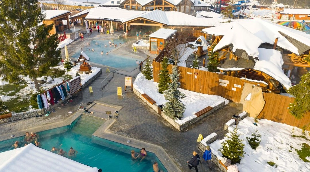 Zimowy widok z góry na kompleks Gorący Potok w Szaflarach, baseny termalne otoczone śniegiem.