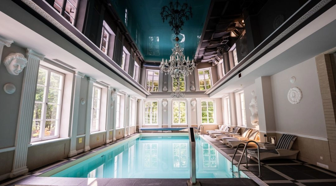 Wnętrze basenu w Pałacu Alexandrinum z kryształowym żyrandolem i klasyczną architekturą.