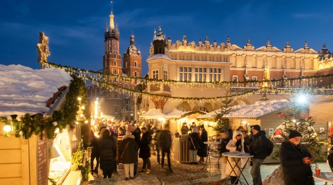 Krakowski Rynek Główny zimą, jarmark świąteczny z choinką i Sukiennicami w tle.